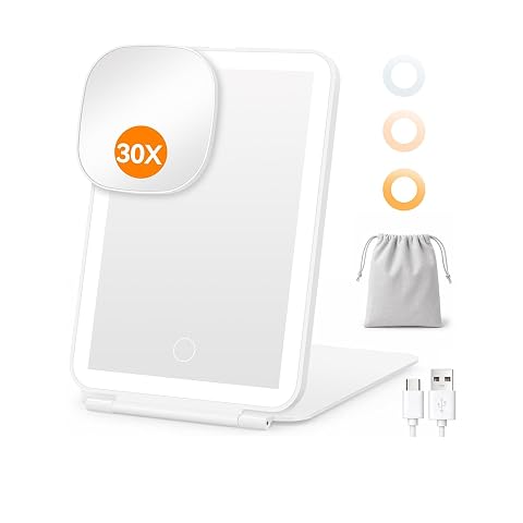 Miroir de maquillage blanc pliable avec LED, miroir grossissant détaché et accessoires posés sur une coiffeuse.