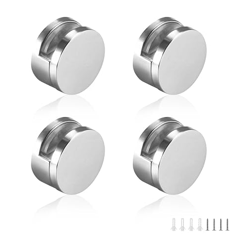 Quatre clips ronds chromés pour miroir, avec leurs vis et chevilles, posés près d’un miroir.