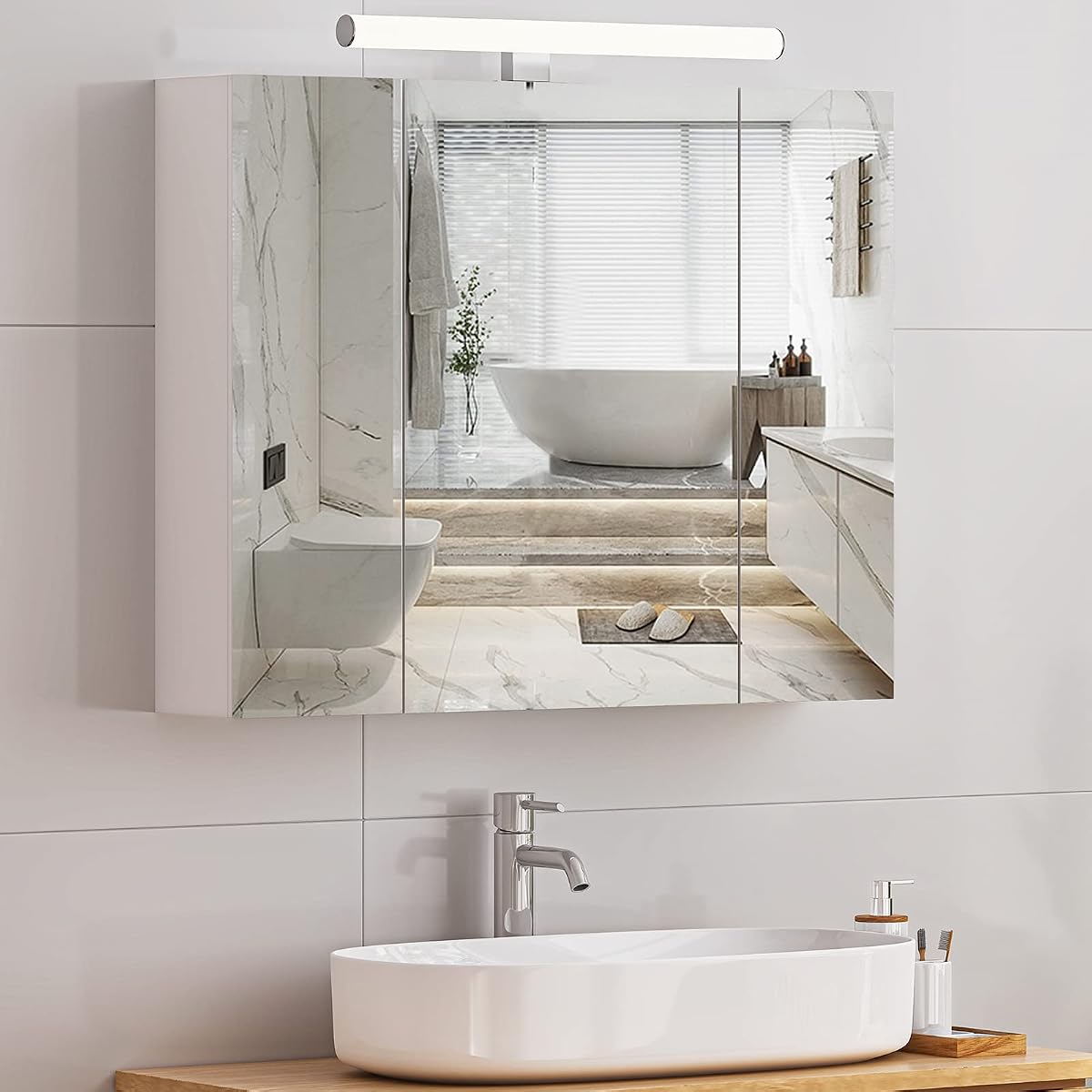 Armoire de toilette blanche à trois portes miroir, éclairage LED et prise intérieure au-dessus d’un lavabo