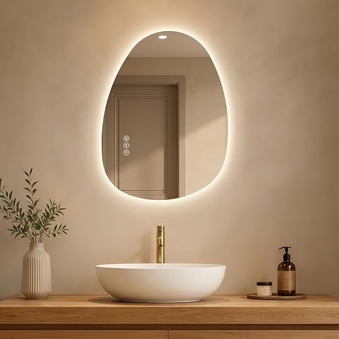 Miroir de salle de bain LED asymétrique rétroéclairé, installé sur un mur en pierre claire.