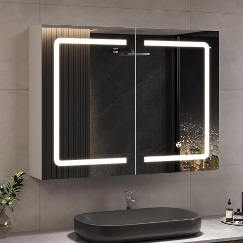 Armoire blanche à deux portes miroir avec éclairage LED et prise intégrée, installée au-dessus d’un lavabo.